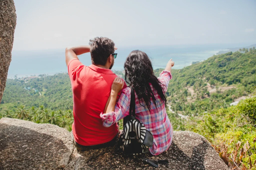 Pareja de recién casados sentados en una roca contemplando la vista en Cartagena de Indias, con vista a la ciudad amurallada de fondo.